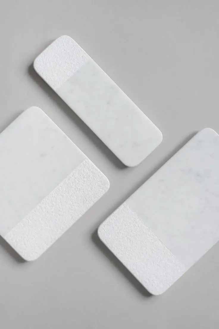 three pieces of white marble sitting on top of a gray table