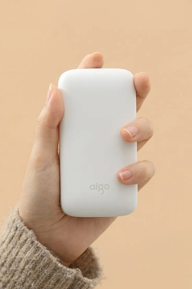 a hand holding an iphone in front of a beige background with